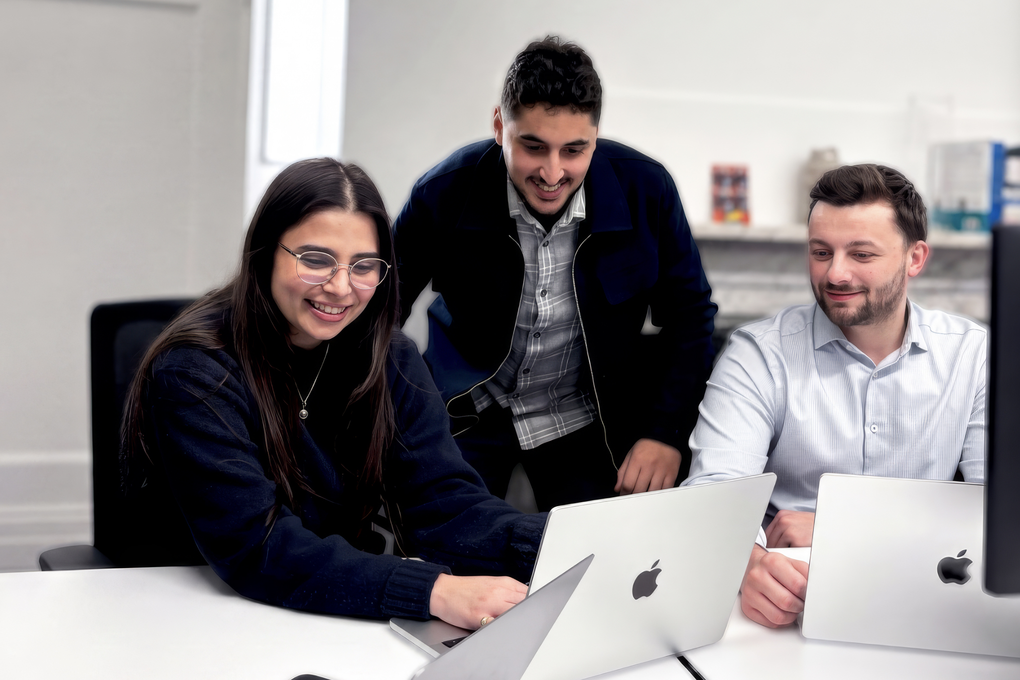 Three coworkers collaborating around laptops in office
