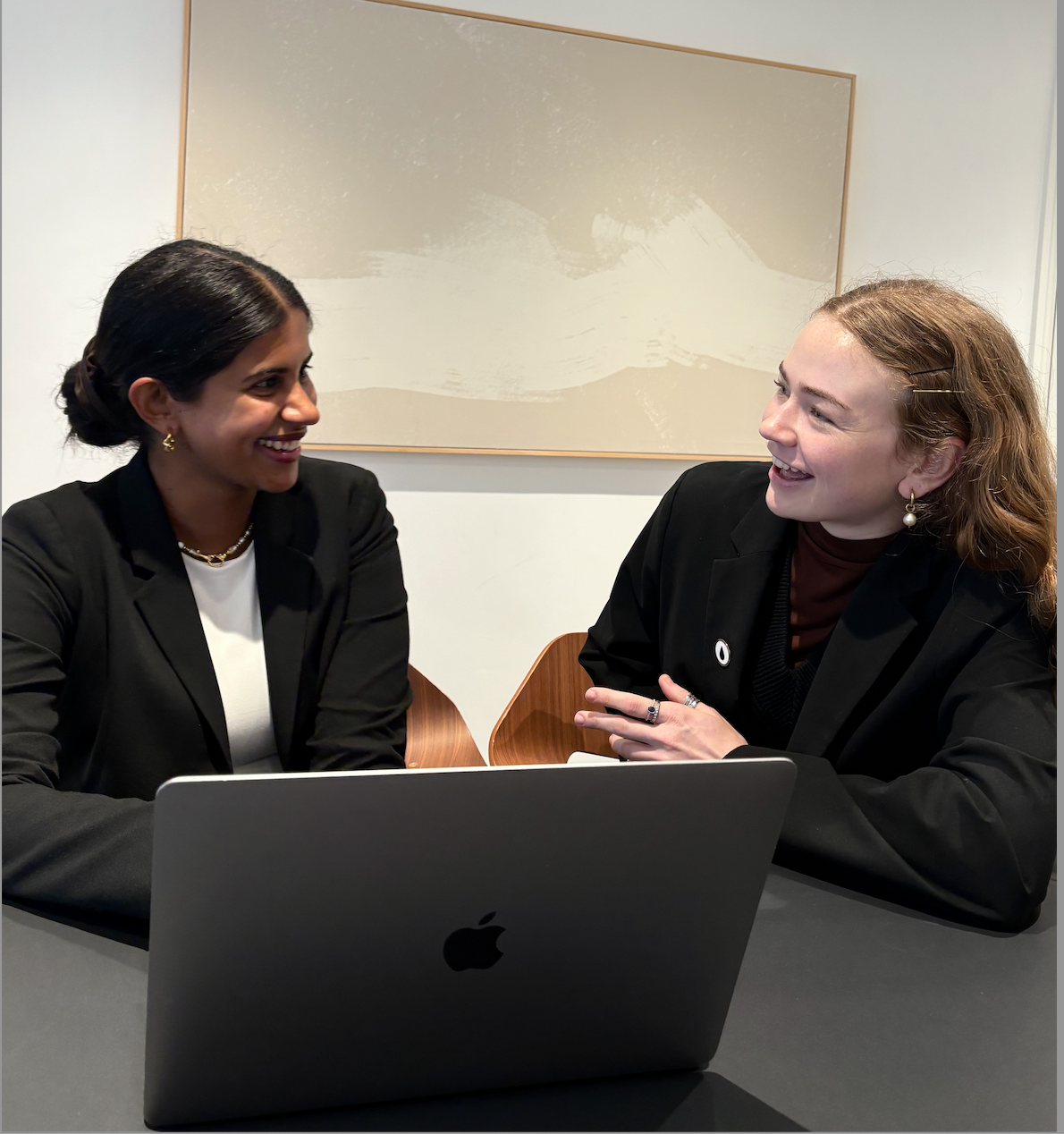 Two professionals smiling over laptop at office table